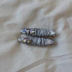 Detail of silver pleated PU fabric hair clips with heart-shaped rhinestone decorations
