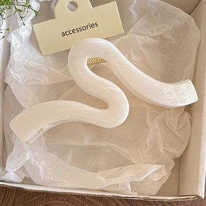 Makroansicht der perlmuttweißen Haarklammer mit Marmoreffekt und goldener Feder
