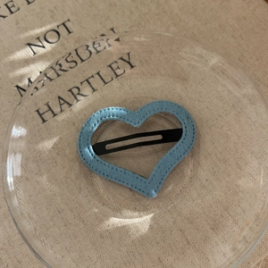 Minimalist light blue denim heart-shaped hollow hair clip on an elegant glass plate