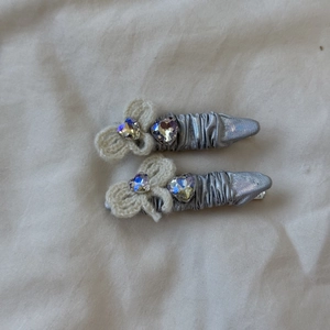 Detail of silver pleated PU clips featuring handmade white bows and heart crystal accents