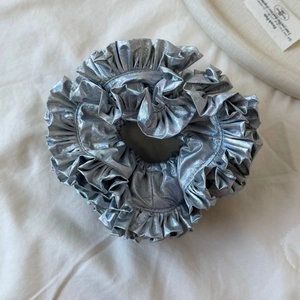 Macro shot of oversized silver metallic scrunchie with holographic laser pleated texture
