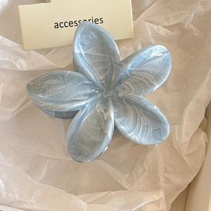 Detail von blau marmorierter Blumen-Haarklammer auf weißem Dekopapier für das Haarstyling