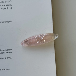 Close-up of a pink resin hair clip with silver glitter on an open book background