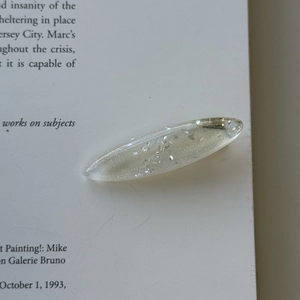 Macro detail of a translucent resin hair clip with silver glitter on a book page