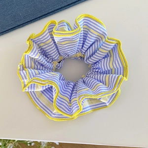 Détail d'un chouchou rayé bleu et blanc avec bordure jaune sur fond en denim bleu