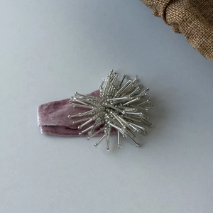 Detail of pink velvet BB clip with silver beaded starburst pattern on grey background