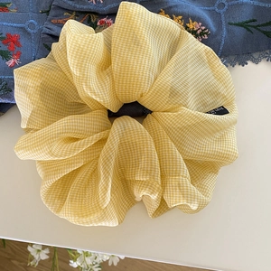 Dettaglio di elastico scrunchie in organza a quadretti gialli con etichetta