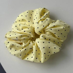 Détail d'un chouchou jaune clair à motif cœur avec étiquette en tissu de qualité