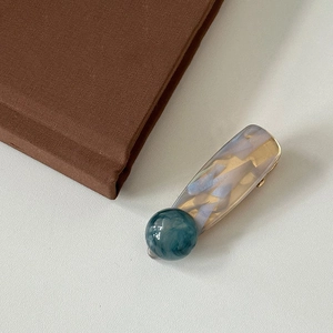 Detailed close-up of marble pattern hair clip with gold metal base on white texture