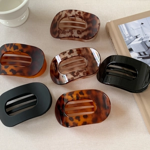 Set of 6 large oval cutout claw clips in tortoiseshell and black resin on linen surface