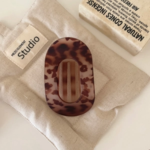 Close-up of tortoise shell oval hair claw clip with cutout design on vintage linen