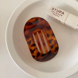 Detailed close-up of tortoise shell pattern acetate hair clip on a white ceramic plate