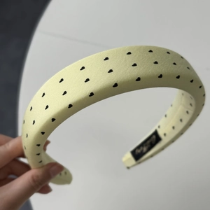 Détail d'un bandeau large jaune clair avec motif de cœur noir et texture en satin