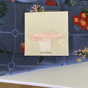Dettaglio del fermaglio ovale rosa con glitter su tessuto ricamato blu scuro