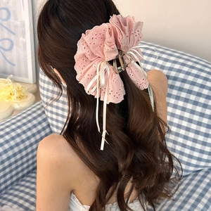 Vue détaillée d'une grande pince à cheveux en dentelle rose avec rubans blancs