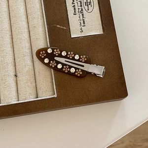 Detail of French vintage hair clip featuring acetate floral rhinestones on wooden jewelry box