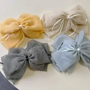 Set of four sheer plaid bow hair clips in yellow, beige, black, and light blue colors