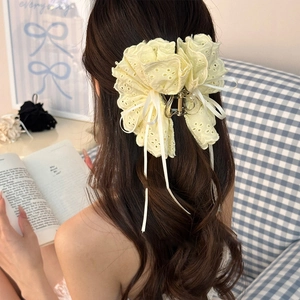 Vue détaillée d'une pince à cheveux en dentelle crème avec de longs rubans sur un modèle