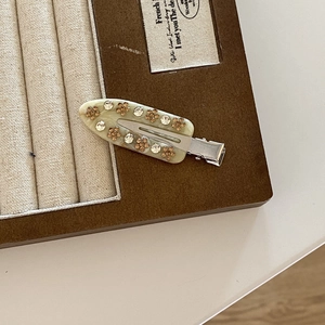Detail view of French vintage beige resin hair clip with amber rhinestone flower pattern
