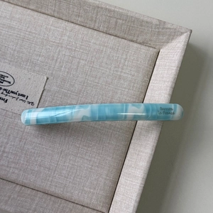 Close-up of blue and white marble acetate hair clip with Barrette La France gold lettering