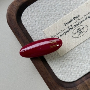 Dettaglio del fermaglio ovale bordeaux in acetato con scritta dorata France Handmade