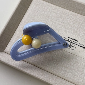 Detail of light purple glitter hair claw with yellow and cream bead accents on tray