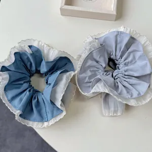Blue double-layered scrunchies with white pleated lace trim on a white background