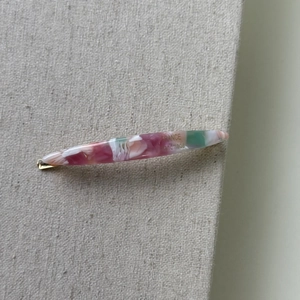 Close-up of pink and green marbled acetate hair clip with gold metal clip and handmade engraving