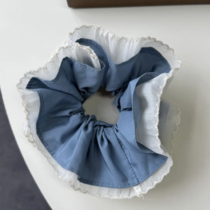 Macro detail of large blue fabric scrunchie with white sheer mesh and delicate lace edges