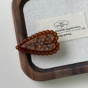 Macro view of French heart hair clip with colorful rhinestones on amber acetate base