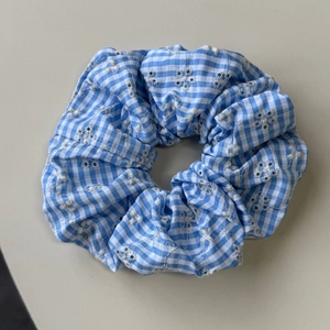 Close-up of blue and white gingham scrunchie with delicate floral embroidery details