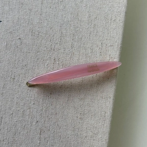 Macro detail of pink acetate leaf hair clip with gold France Handmade lettering