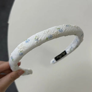 Detail of floral embroidery and blue flower print on white fabric headband