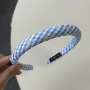 Close-up of blue gingham headband featuring delicate white daisy floral embroidery detail