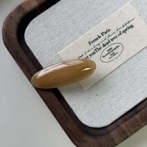 Dettaglio di un fermaglio per capelli in acetato ambrato con scritta dorata fatta a mano