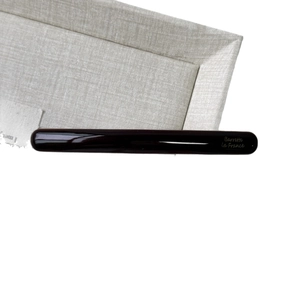 Minimalist glossy dark brown acetate hair barrette with gold French text on fabric tray