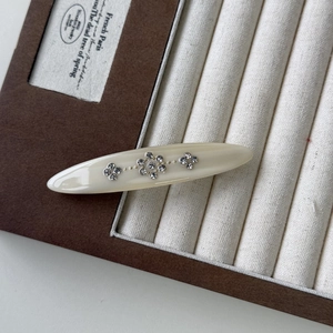 Vintage cream acetate hair clip with floral rhinestones on velvet jewelry tray