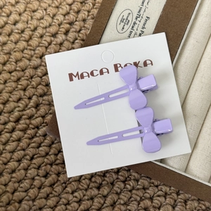 Detailed view of two purple candy-colored bow hair clips on a white display card