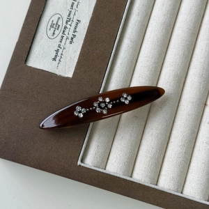 Detailed macro view of acetate leaf hair clip with rhinestones and tortoiseshell texture