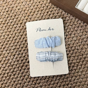 Detail of light blue and striped fabric bow hair clips on premium display card
