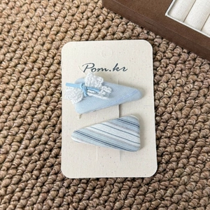 Detail view of light blue lace bow and striped fabric triangle hair clips on display card