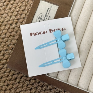 Close-up of sky blue bow-shaped hair clips on display card with a textured background