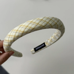 Detail eines gelb-karierten Stoff-Hairreifens mit handgemachtem Label und Nahtstruktur