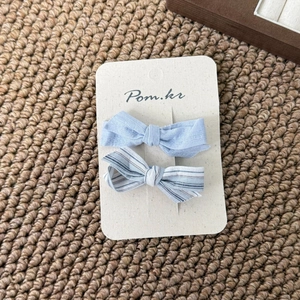 Detail of light blue bow hair clips in solid and striped cotton fabric on card