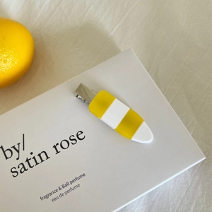 Sweet yellow and white striped acetate hair clip on a minimalist aesthetic background