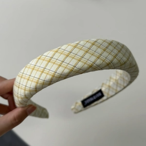 Detailaufnahme des schwarzen Handmade-Etiketts auf dem gelben karierten Haarband