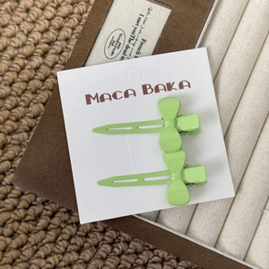 Detail view of two mint green bow hair clips on a white card board packaging
