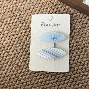 Detail view of light blue fabric hair clips with floral mesh and striped patterns on card