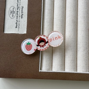 Gros plan d'une pince à cheveux en acrylique rose avec motif fille et fraises