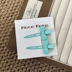Close-up of two sky blue bow hair clips on a white display card in an accessory box